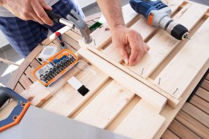 hands driving nail with hammer into wooden shelf 1